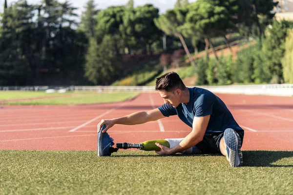 Atleta hombre discapacitado estiramiento con prótesis de pierna . — Foto de Stock