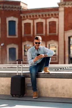 İş adamı sokakta akıllı telefonunu kullanıyor..