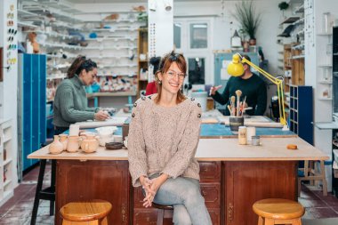 Çömlekçilik akademisinin başarılı sahibinin gülümseyen ve kameraya bakan resmi..