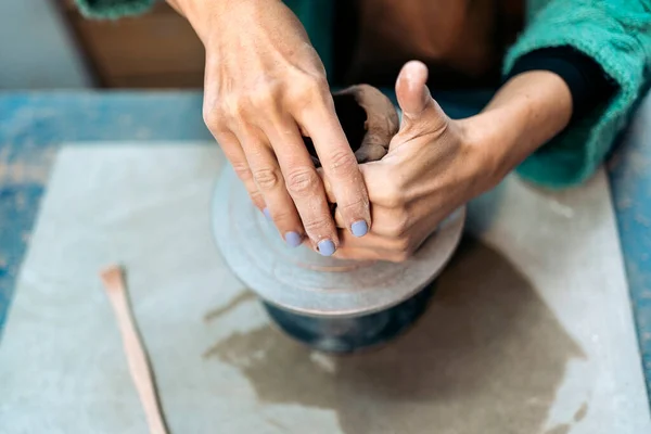 Stock photo of unrecognized person shaping clay in art pottery workshop.