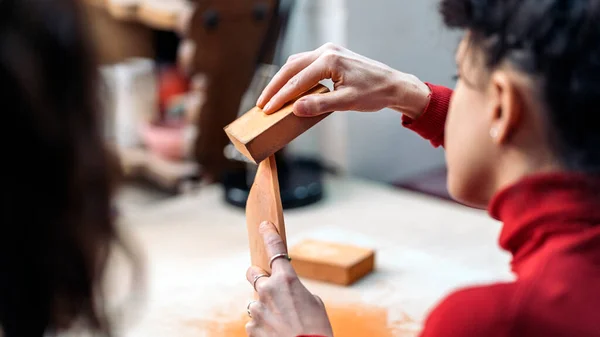 Stock photo of unrecognized person sanding pot in pottery class.