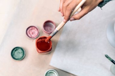 Çömlekçilik dersinde boya fırçası kullanan tanınmamış kişinin resmi.
