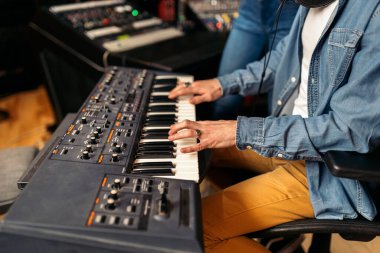 Profesyonel müzik stüdyosunda elektronik piyano klavyesi çalan tanınmamış müzisyenin resmi..