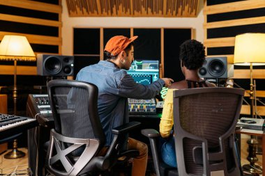 Profesyonel müzik stüdyosunda zenci şarkıcıyla çalışan erkek müzik yapımcısının stok fotoğrafı..