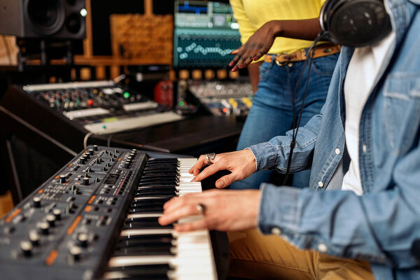 Stock photo of unrecognized musician in professional music studio playing electronic piano keyboard.