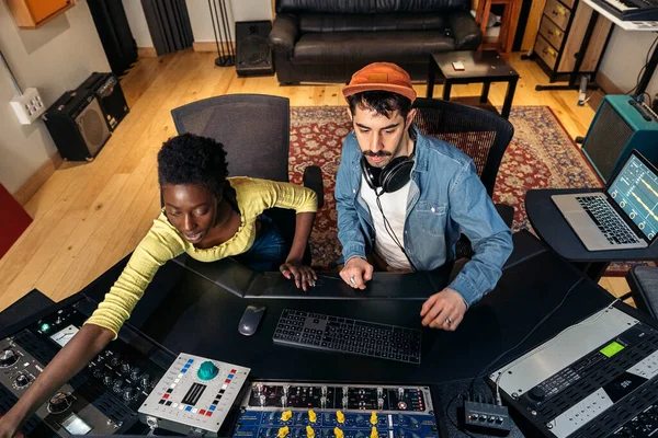 Stock photo of male music producer working with black singer in cool music studio.