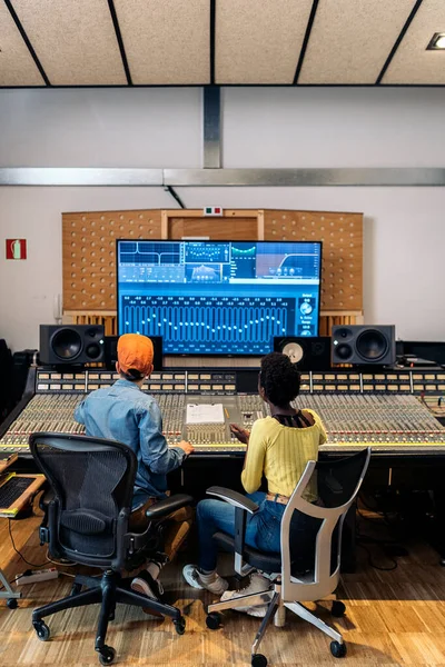 Stock photo of male music producer working with black singer in professional music studio.
