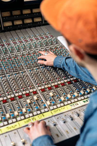 Stock photo of unrecognized person using panel control in professional music studio.