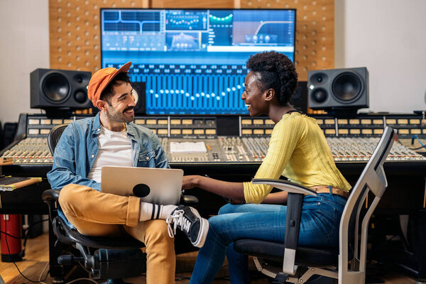 Stock photo of male music producer working with black singer in professional music studio.