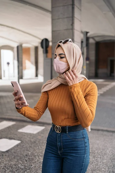 Mulher Muçulmana Jovem Bonita Usando Máscara Protetora Usando Seu Telefone — Fotografia de Stock