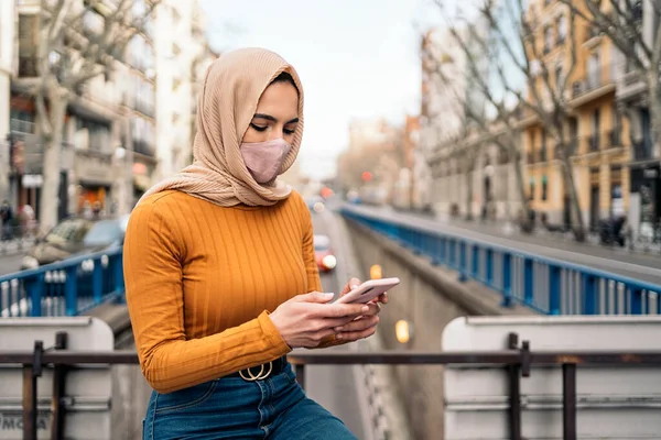 Mulher Muçulmana Muito Jovem Usando Máscara Facial Usando Seu Telefone — Fotografia de Stock