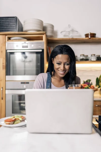 Happy Black Woman Drinking Juice Kitchen Home Using Computer — Stok Foto
