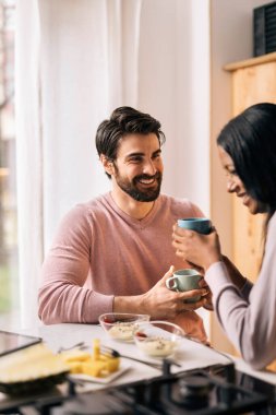 Yakışıklı bir adam ve kız arkadaşı evdeki mutfakta kahvaltı yapıyorlar..