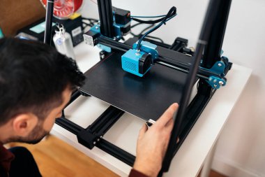 Stock photo of unrecognized technician fixing modern 3d printer.