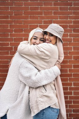 Affective young women wearing hijab smiling and looking at camera.