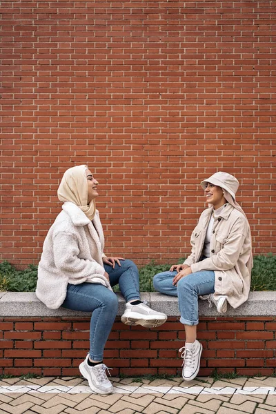 Jovens Mulheres Alegres Usando Hijab Conversando Sentadas Banco — Fotografia de Stock