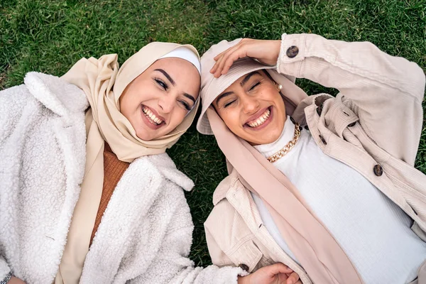Cheerful Young Women Wearing Hijab Having Fun While Lying Grass — Fotografia de Stock