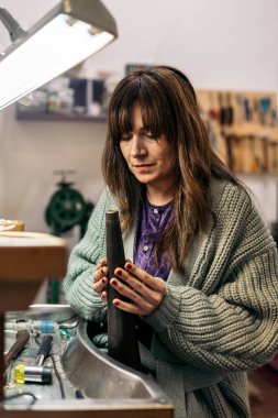 Konsantre kadın mücevher atölyesinde özel aletler kullanıyor..