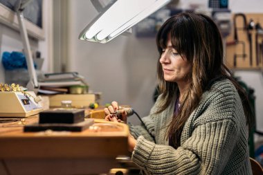 Mücevher atölyesinde çalışan konsantre bir kadının stok fotoğrafı..