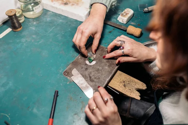 Unrecognized craftswomen working jewelry workshop using tools.