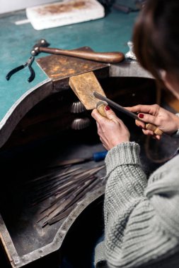 Unrecognized craftswoman working jewelry workshop.