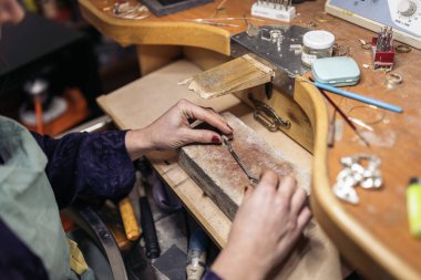 Unrecognized woman using tools in jewelry workshop.