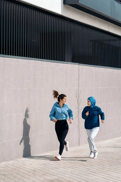 Active Young Female Friends Running Street Smiling One Them Wearing — Stock Photo, Image