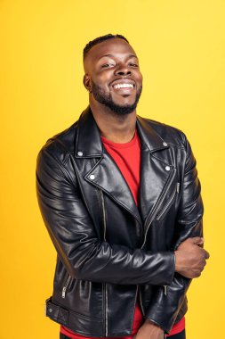 Confident black man wearing black leather jacket smiling and looking at camera in studio shot.