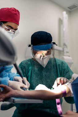 Professionals medic workers wearing latex gloves drawing blood to unrecognized patient.