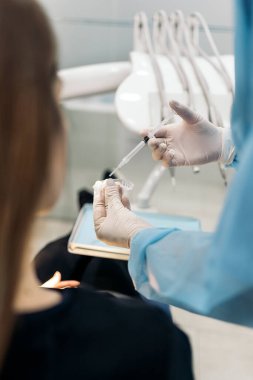 Unrecognized dentist wearing latex gloves explaining to patient how to use teeth covers.