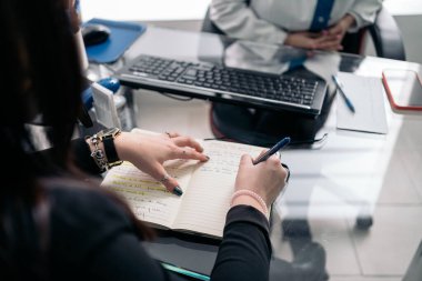 Unrecognized dentist woman wearing face mask due to covid19 working in her office and taking notes.