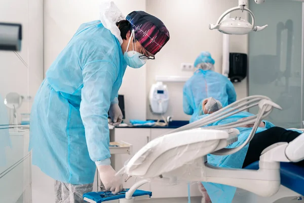 Dentist work team wearing face mask and protective clothes working with unrecognized patient.