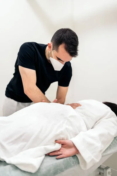 Male Physiotherapist Wearing Face Mask Giving Back Massage Unrecognized Woman — стоковое фото