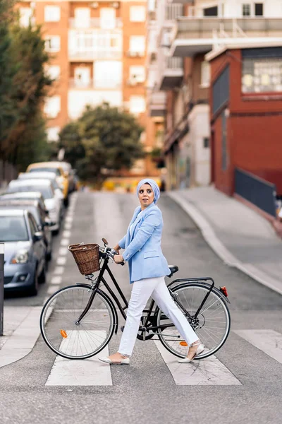 ภาพแนวต งของผ มสวมช ดไฟส าและกางเกงส ขาวเด วยจ กรยานของเธอข ามถนนมองไปด านข ภาพถ่ายสต็อกที่ปลอดค่าลิขสิทธิ์