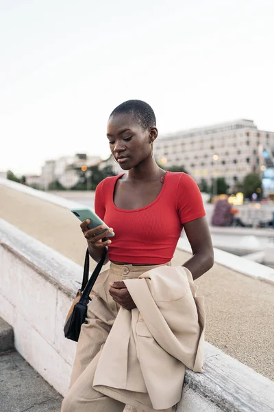 Wanita Muda Afro America Bergaya Menggunakan Telepon Sambil Memegang Jaket — Stok Foto