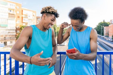 Havalı Afro-Amerikan erkekleri sokakta eğleniyor ve telefonlarını kullanıyor..