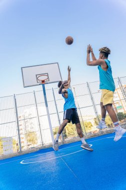 Güçlü ve sağlıklı Afrikalı arkadaşlar basketbol oynuyor ve güneşli bir günde eğleniyorlar..