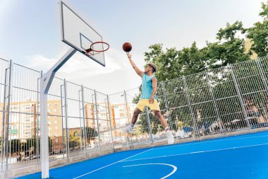 Tanınmayan Afrikalı çocuk spor kıyafetleri giymiş basketbol oynuyor ve top atıyor..