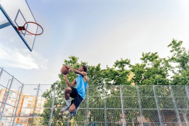 Tanınmayan Afrikalı çocuk spor kıyafetleri giymiş basketbol oynuyor ve top atıyor..