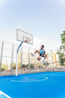Tanınmayan Afrikalı çocuk spor kıyafetleri giymiş basketbol oynuyor ve top atıyor..
