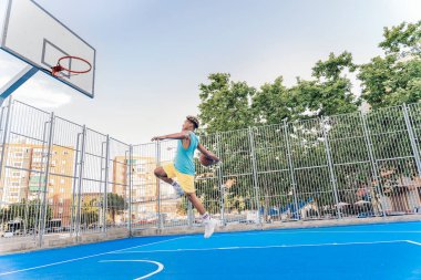 Tanınmayan Afrikalı çocuk spor kıyafetleri giymiş basketbol oynuyor ve top atıyor..