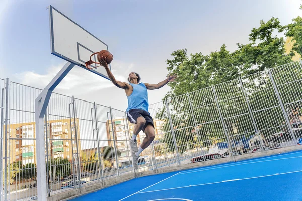 Unrecognized african boy wearing sports clothes playing basketball and throwing the ball.