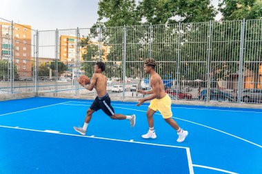 Güçlü ve sağlıklı Afrikalı arkadaşlar basketbol oynuyor ve eğleniyorlar..