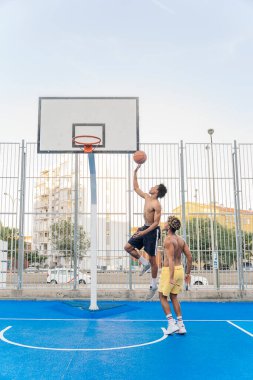 Tanınmayan tişörtsüz Afrikalı arkadaşlar birlikte basketbol oynuyor ve eğleniyorlar..