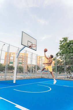 Tanınmayan Afrikalı çocuk spor kıyafetleri giymiş basketbol oynuyor ve top atıyor..