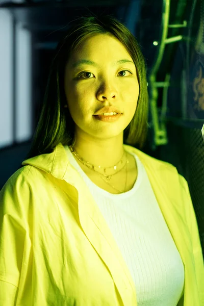 Mooie Aziatische Vrouw Poseren Kijken Naar Camera Tegen Geel Licht — Stockfoto