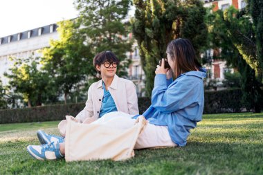 Parktaki Asyalı erkek arkadaşına fotoğraf çeken tanınmamış bir kadın..