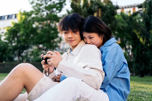 Cute Asian Couple Sitting Park Together Using Camera — Stock Photo, Image