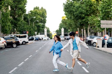 Genç Asyalı bir çift şehirde el ele yürüyor ve güneşli bir günün tadını çıkarıyor..