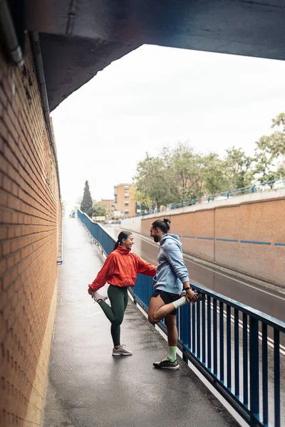 雨の日に走り 笑顔でスポーツウェアを着た若い男とその女性の友人 — ストック写真